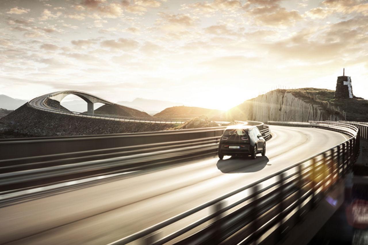 Car driving across bridge into sunset